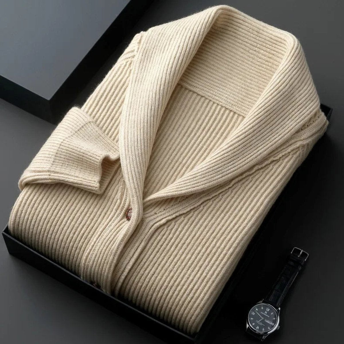 Folded cream ribbed shawl-collar cardigan displayed beside a wristwatch