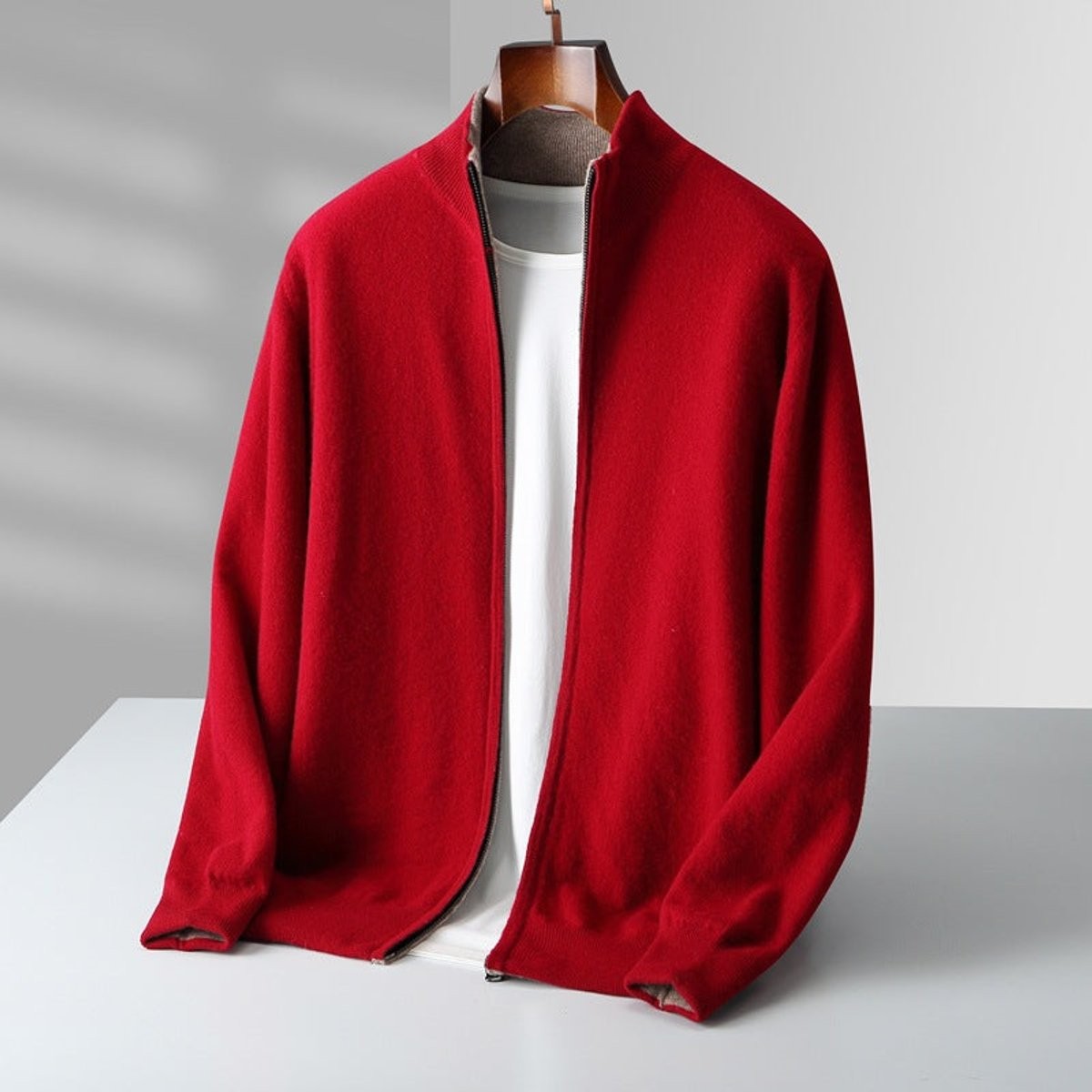 Red knitted cardigan with stand collar displayed on wooden hanger