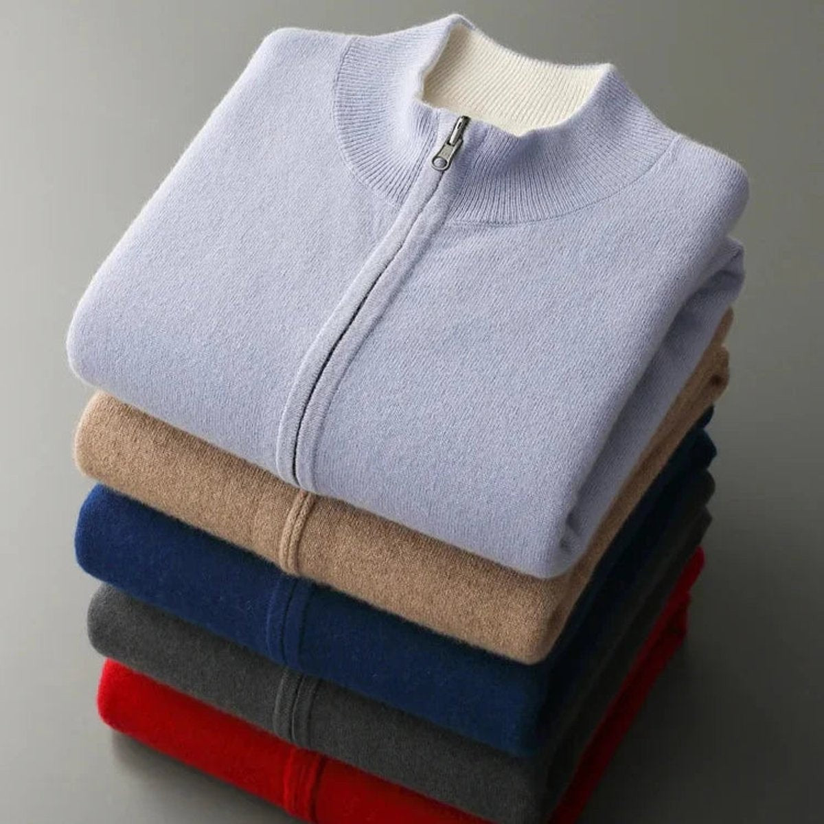 Folded stack of knitted zip cardigans in assorted colours