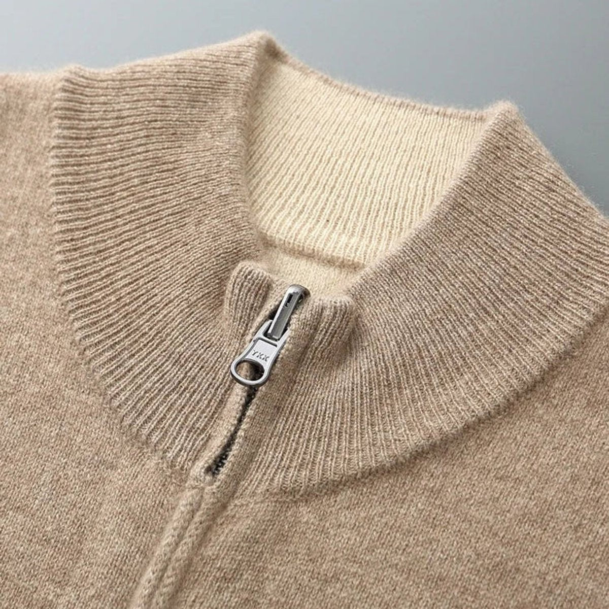 Close-up of beige cardigan collar showing YKK zip pull
