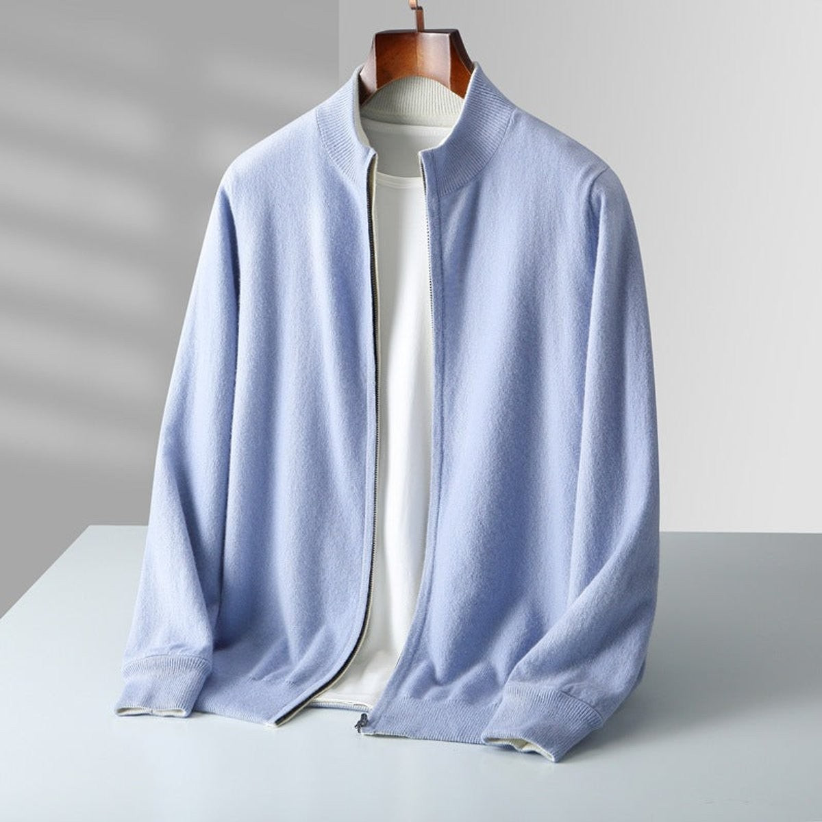 Pale blue knitted cardigan with full zip shown on hanger