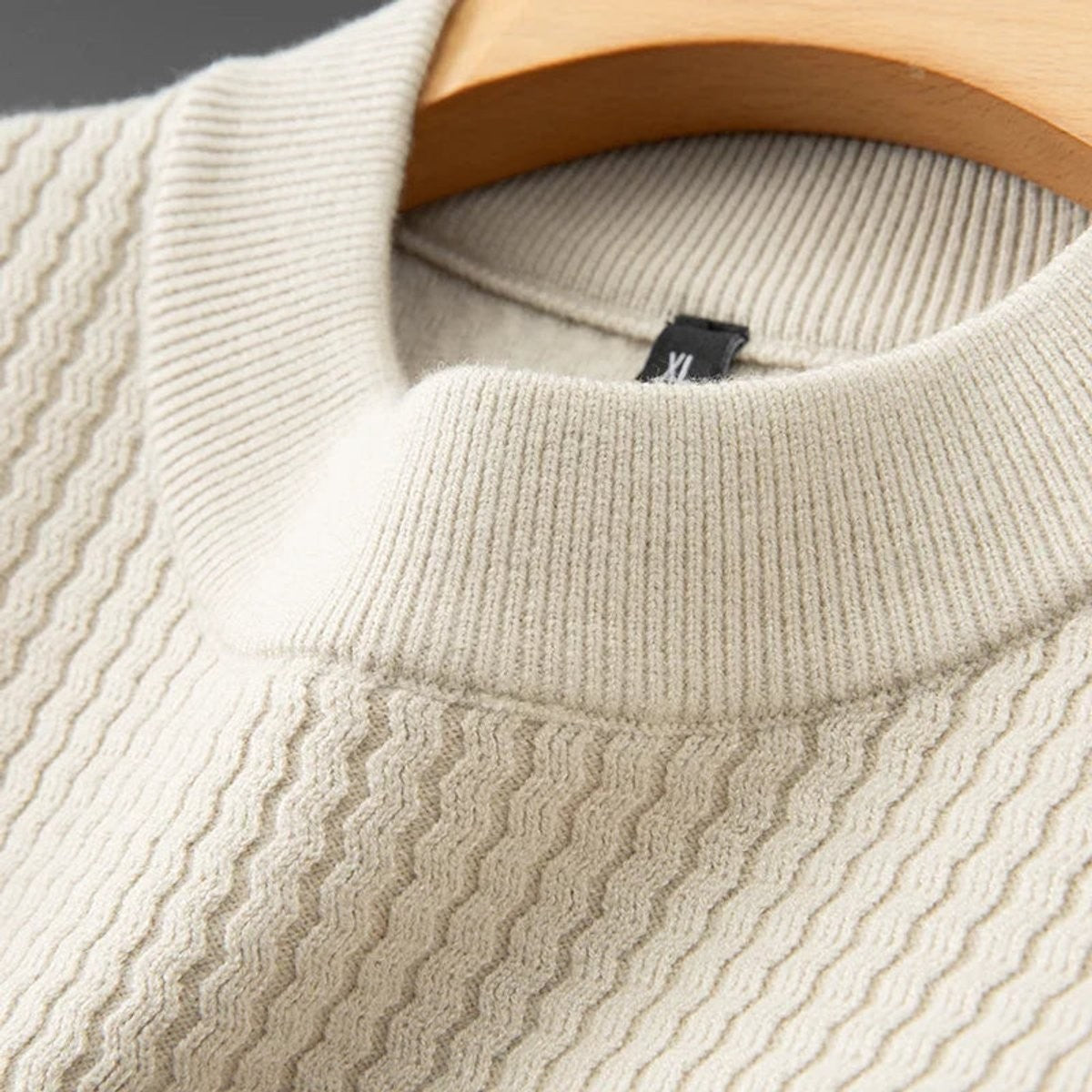 Close-up of ribbed knit collar and fabric texture on beige jumper