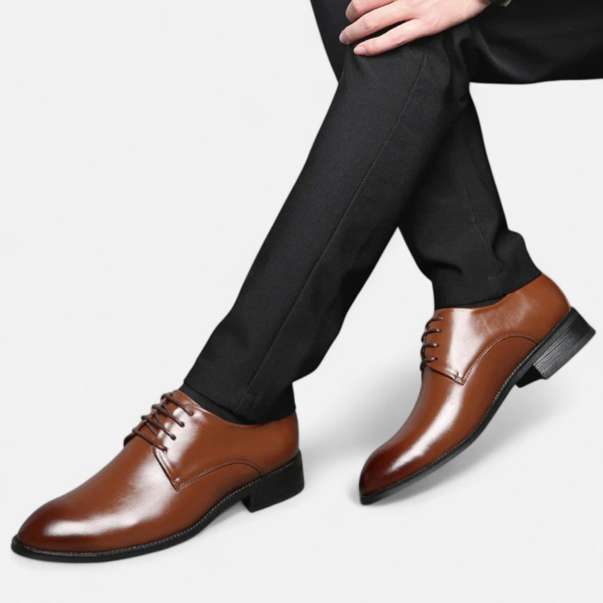 Close-up of tan leather lace-up shoes styled with black tailored trousers