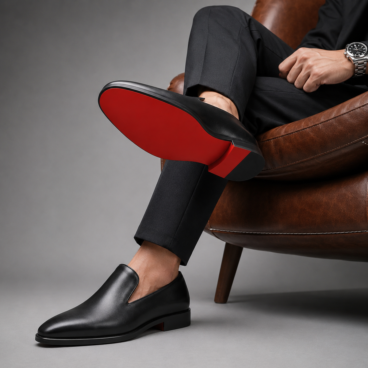 Seated man showing red sole underside of black leather loafer