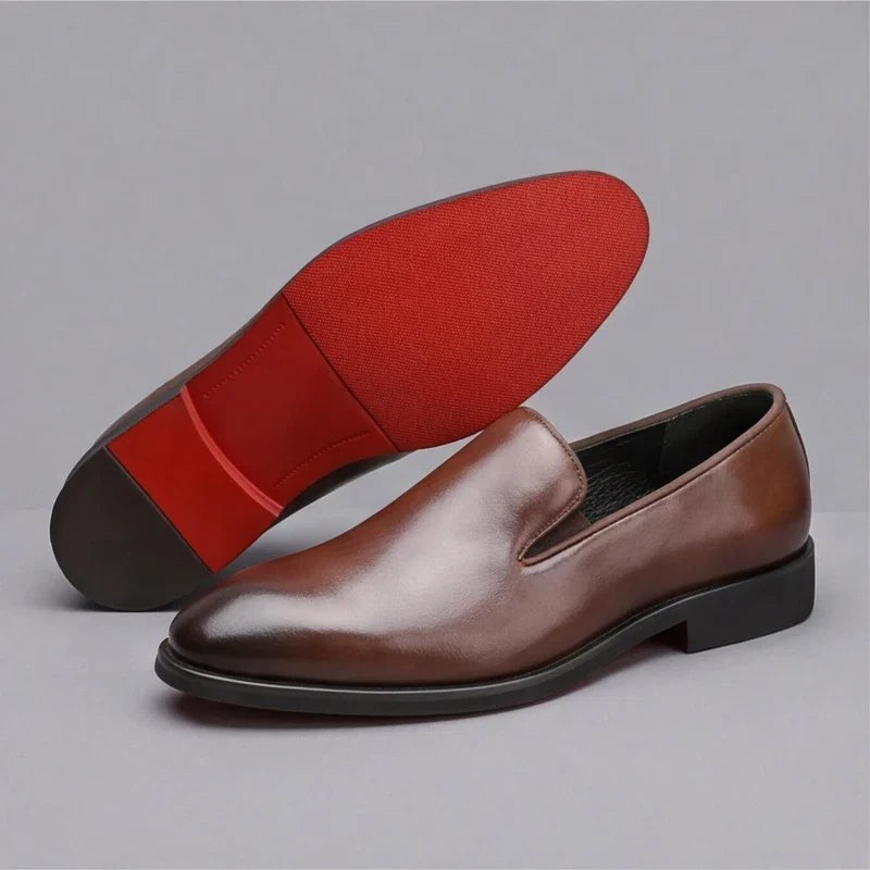 Brown leather loafers paired showing red rubber sole underside