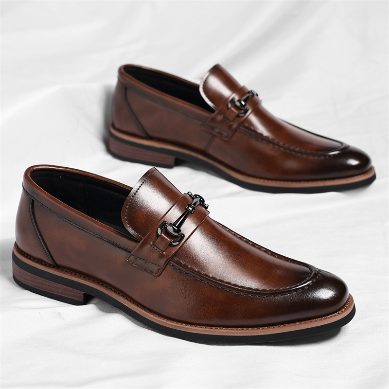 Pair of brown leather loafers showing textured finish and buckle trim