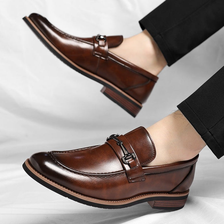 Man's foot showcasing brown leather loafer with metal buckle strap