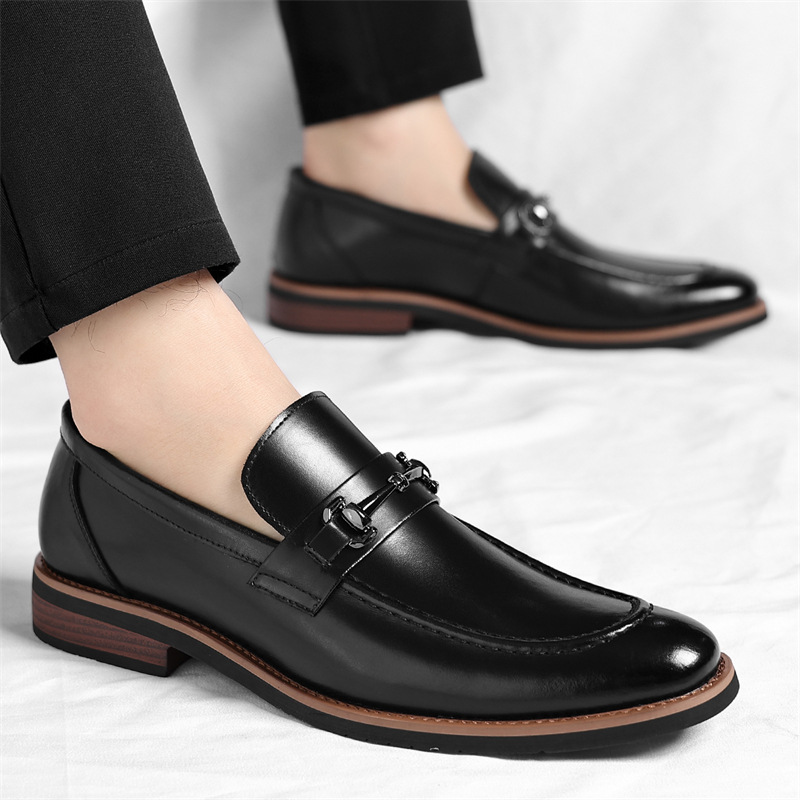 Hand holding brown leather loafer beside matching worn shoe on foot