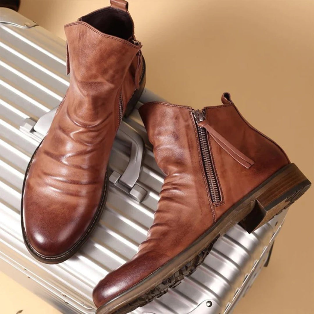 Tan leather ankle boots with side zip resting atop a silver suitcase