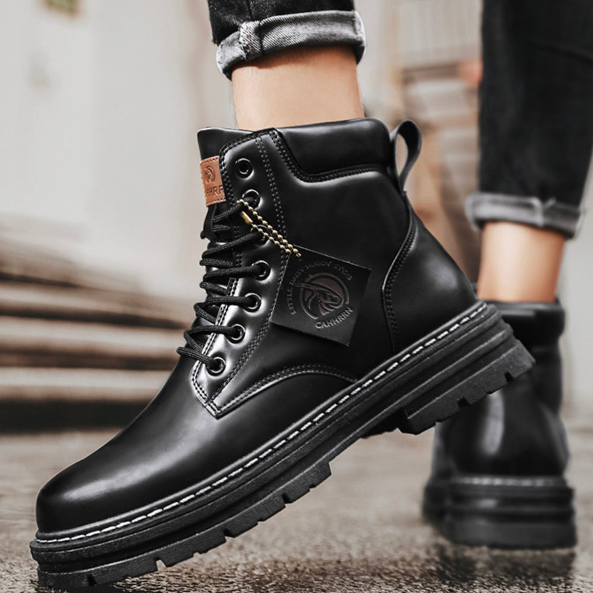 Black leather ankle boots worn on foot, lace-up fastening with rugged sole