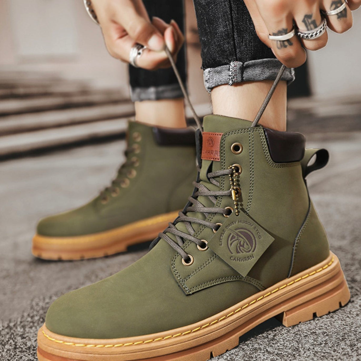 Olive green suede-style work boots being laced up, tan sole and hardware