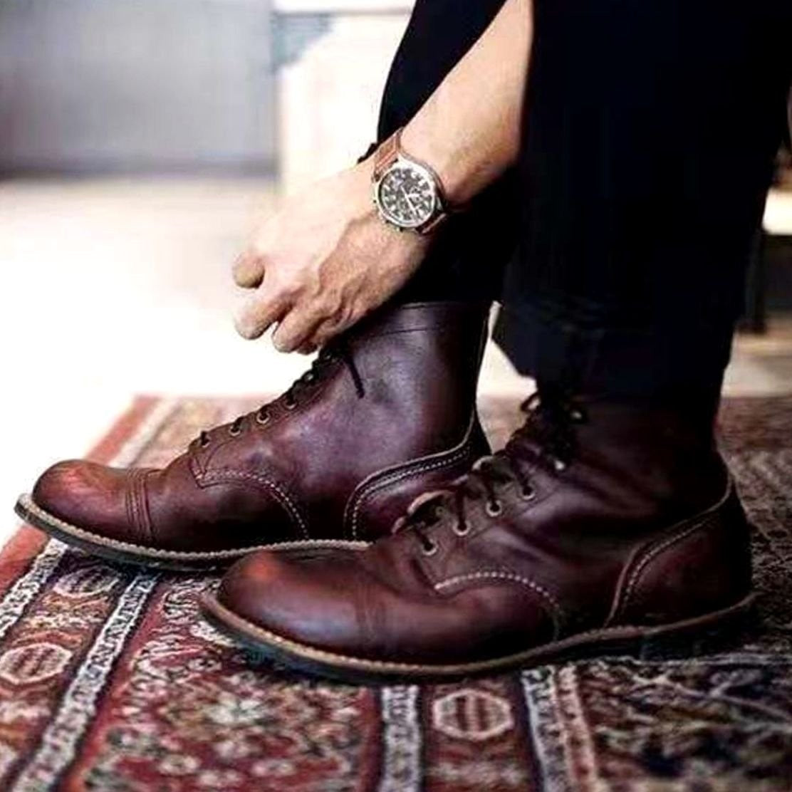 Men's dark brown leather lace-up boots worn with cropped black trousers