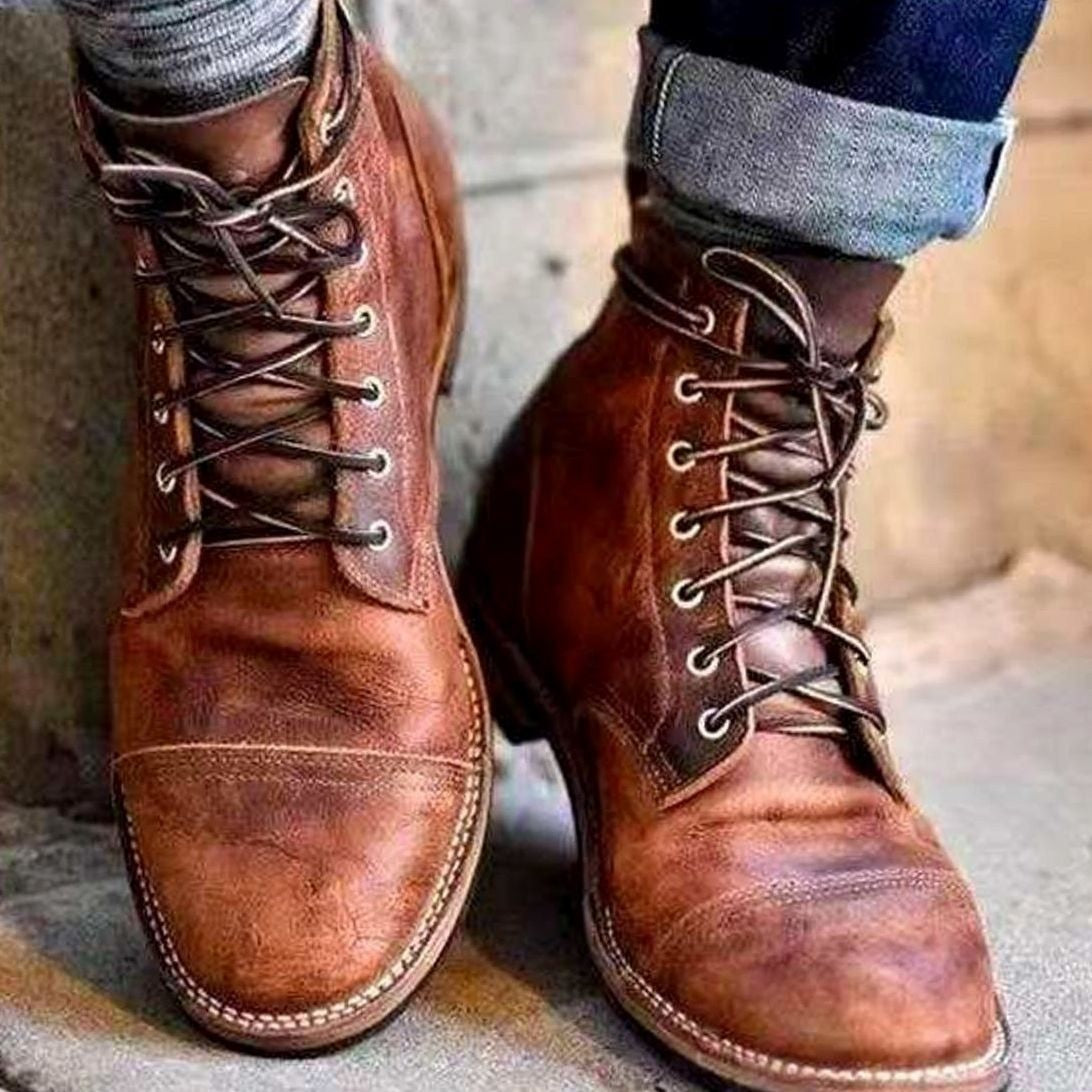 Tan leather lace-up boots with contrast stitching, worn with rolled denim jeans