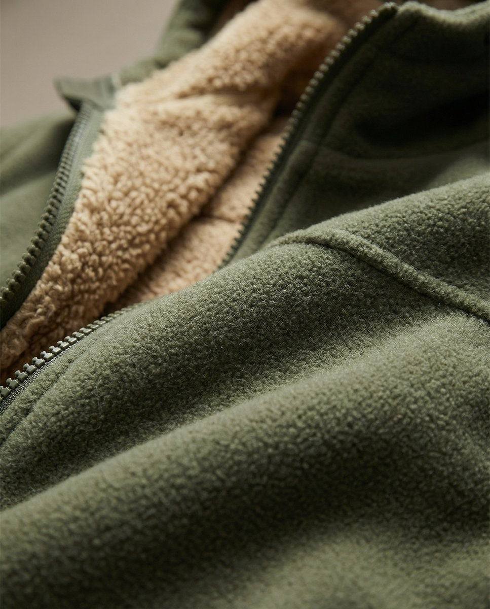 Close-up of olive fleece hoodie zip showing contrasting tan sherpa lining texture