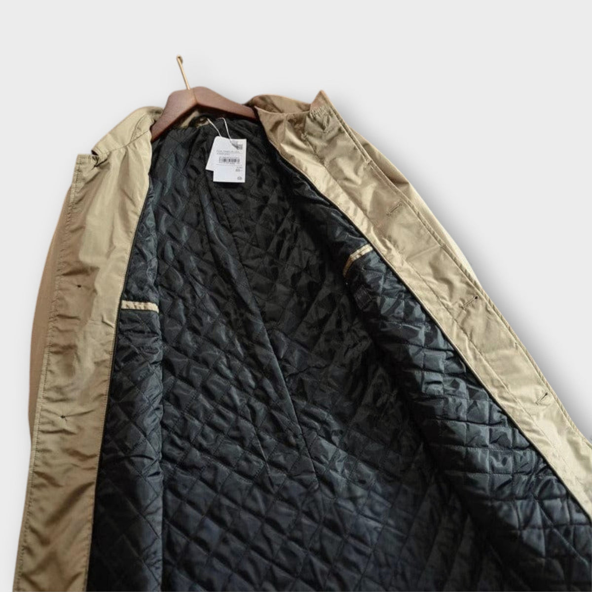 Beige mac coat open to reveal quilted black inner lining