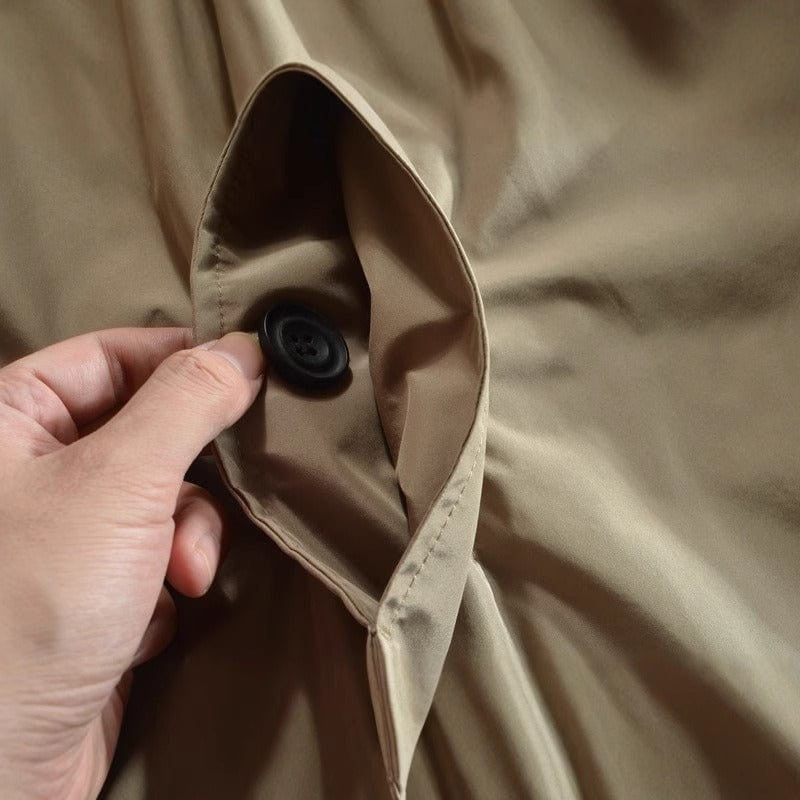 Close-up of button fastening on beige mac coat fabric