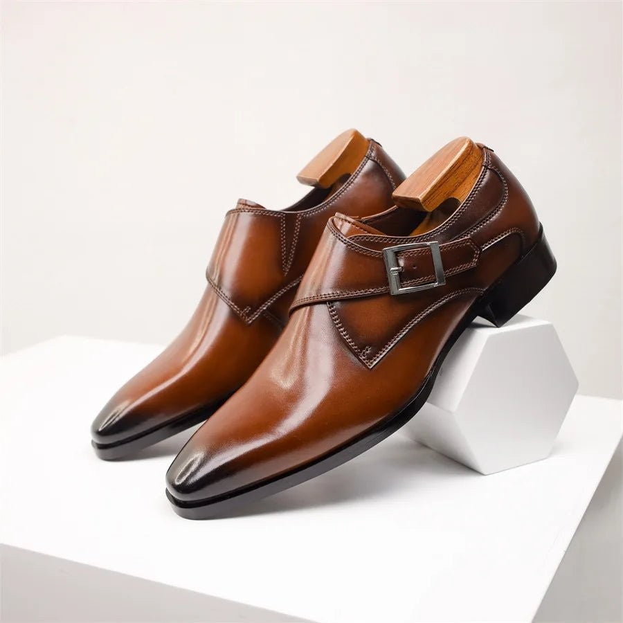 Tan leather monk strap shoes displayed on white geometric block