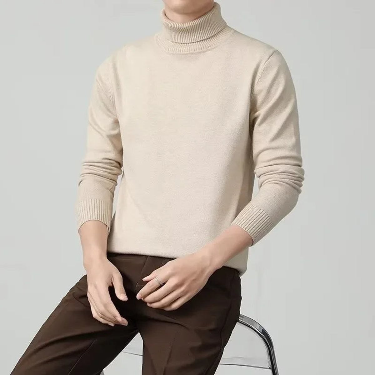 Beige cashmere roll-neck jumper paired with dark brown tailored trousers