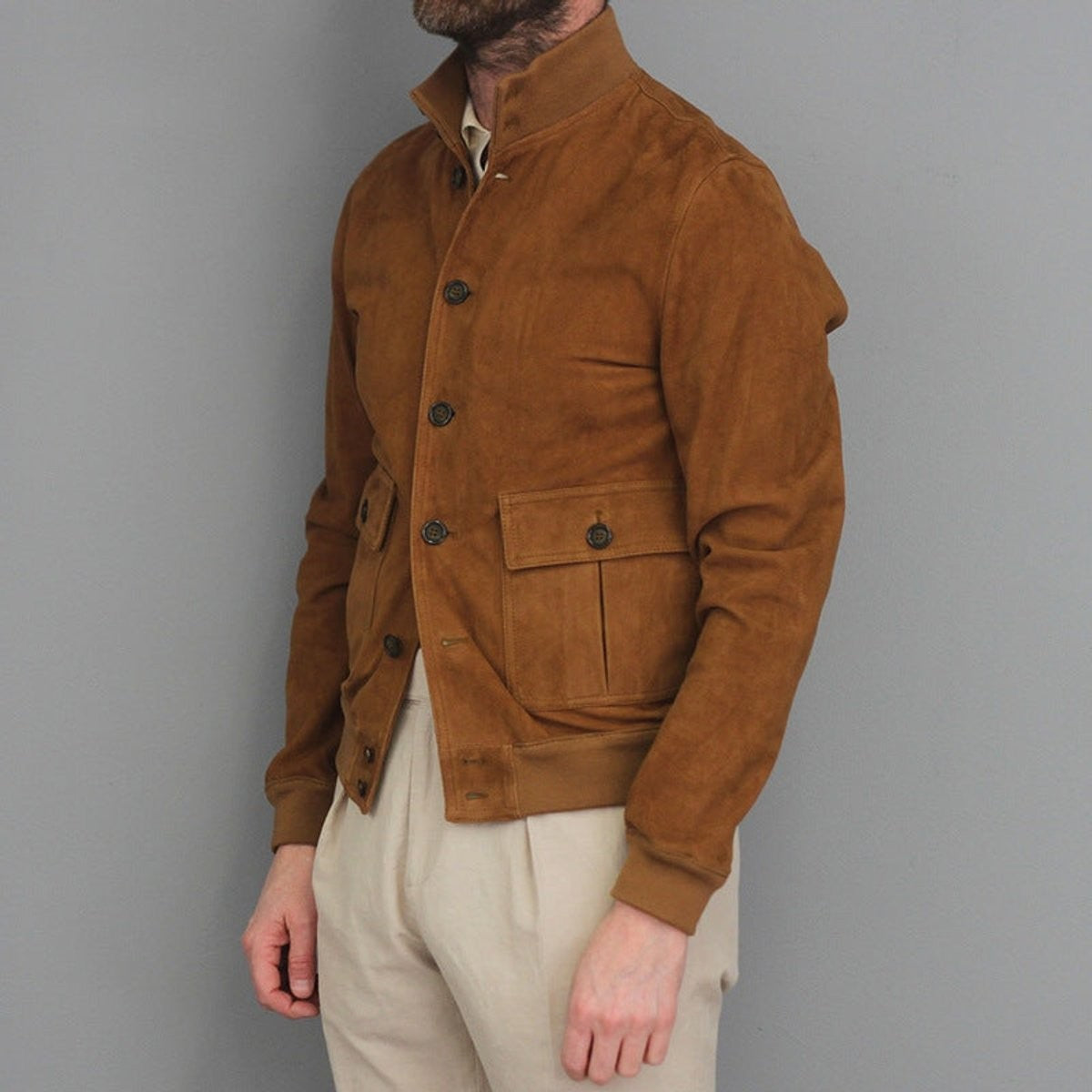 Tan suede bomber jacket with stand collar and buttoned flap pockets, side view