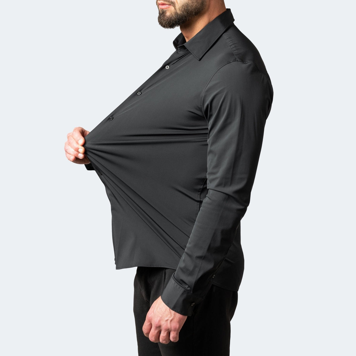 Model tugging black slim-fit stretch shirt to reveal fabric elasticity