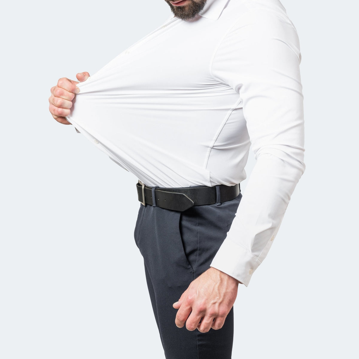 Model stretching white slim-fit shirt to demonstrate flexible fabric