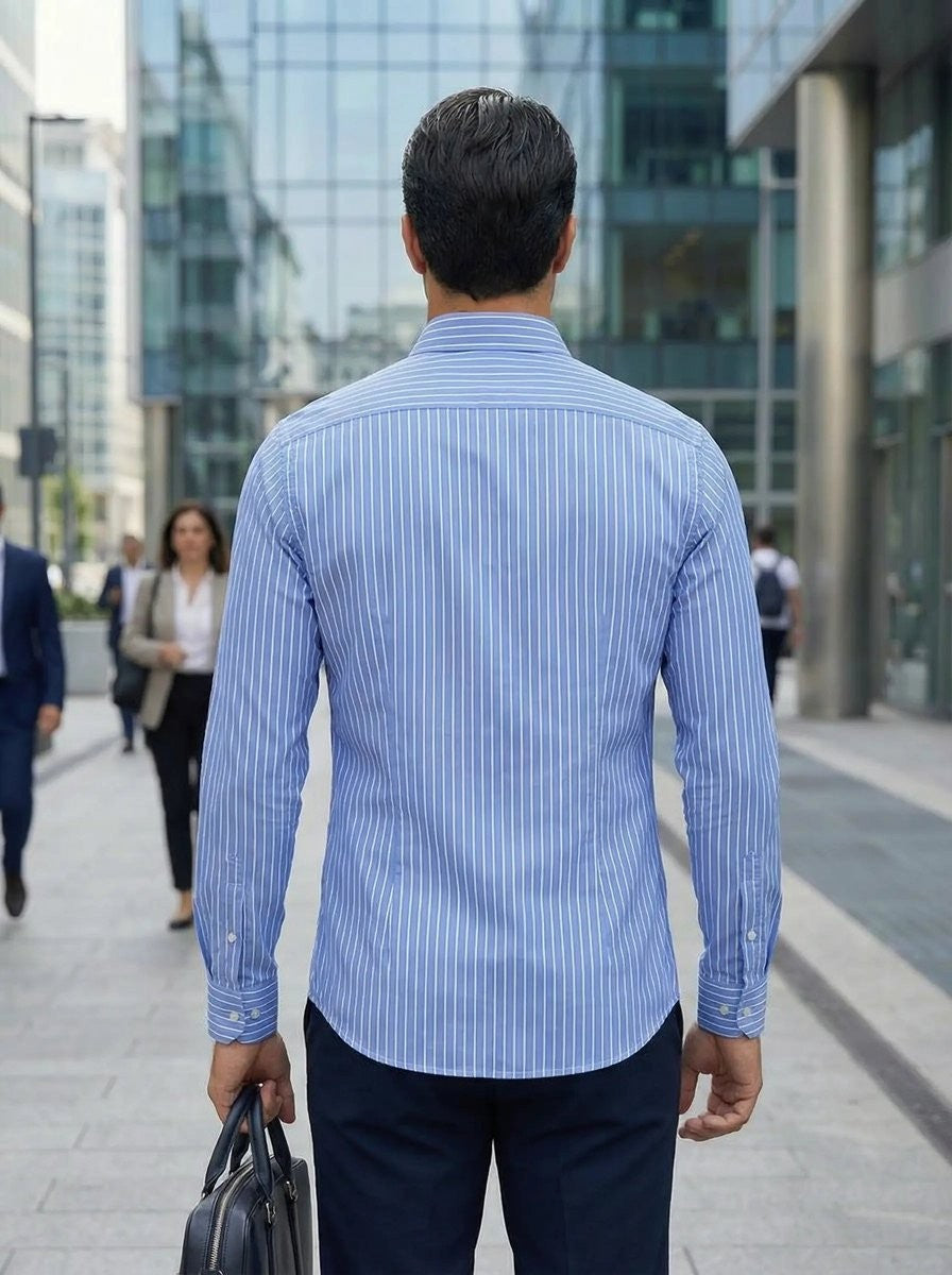 Man wearing light blue striped shirt walking through a city street