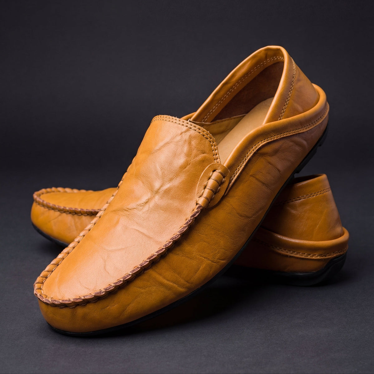 Pair of tan leather moccasins showing stitched sole and soft creased finish