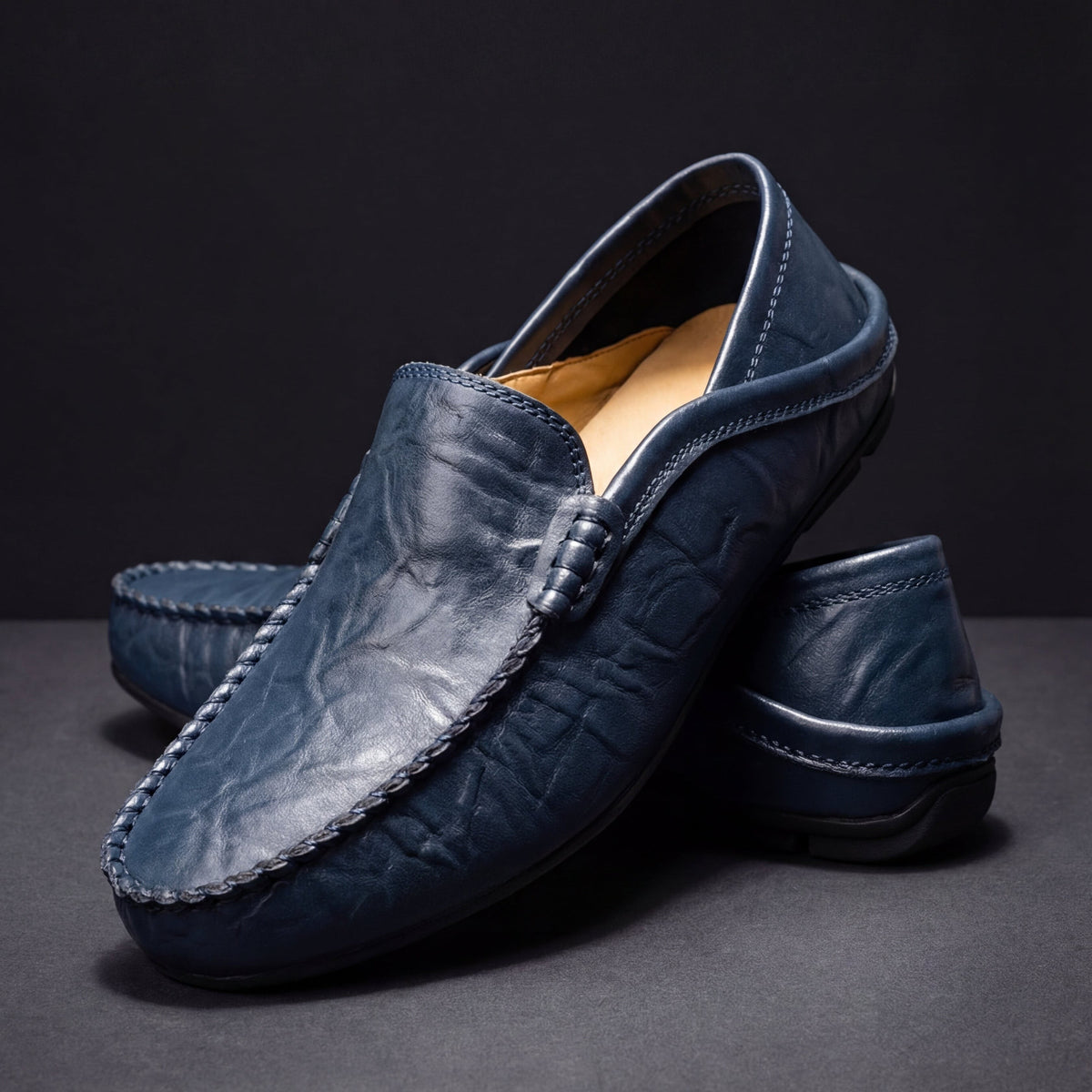 Navy leather slip-on moccasins with braided buckle trim and tan lining