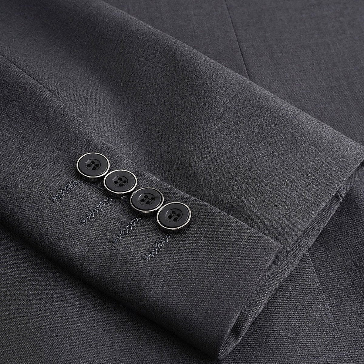 Close-up of charcoal blazer cuff showing four-button detail and stitching