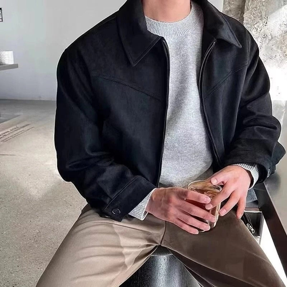 Black suede zip-up bomber jacket worn over grey knit jumper