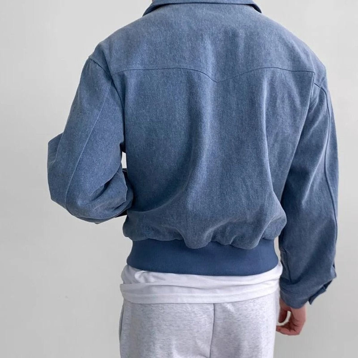 Rear view of blue suede bomber jacket showing ribbed hem detail
