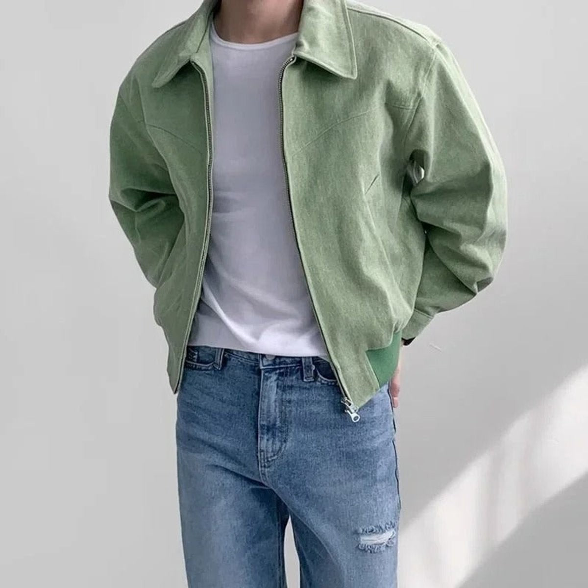 Sage green suede bomber jacket paired with distressed denim jeans