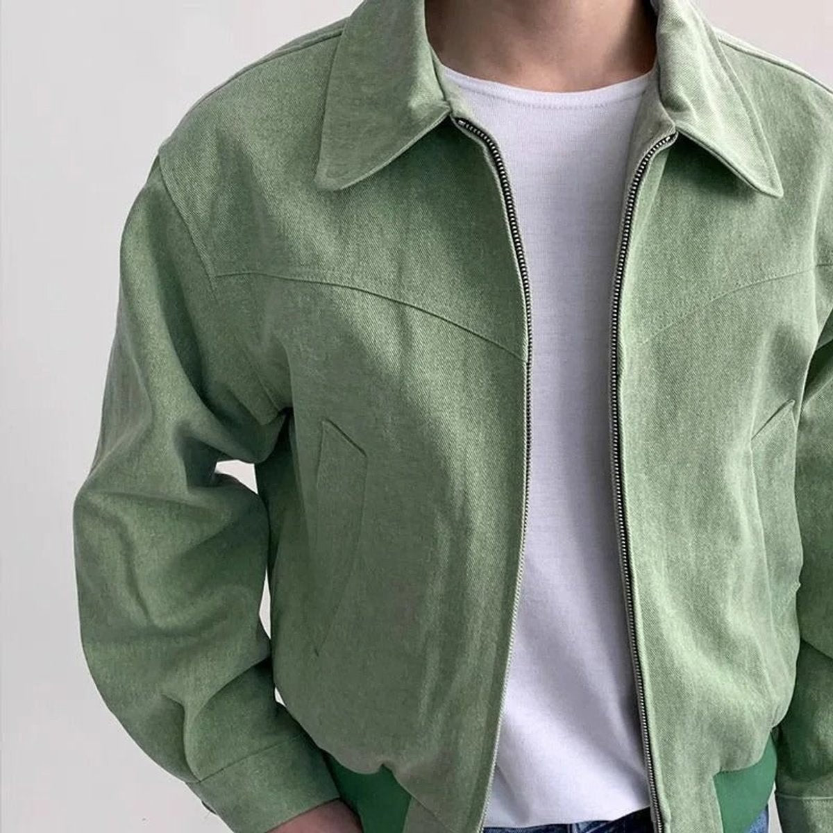 Close-up of sage green suede bomber jacket showing zip and collar