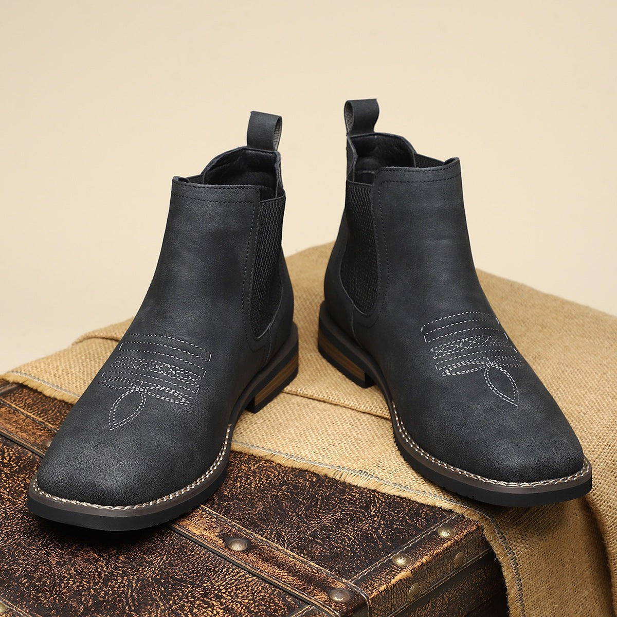Front view of black leather Chelsea boots with decorative stitching