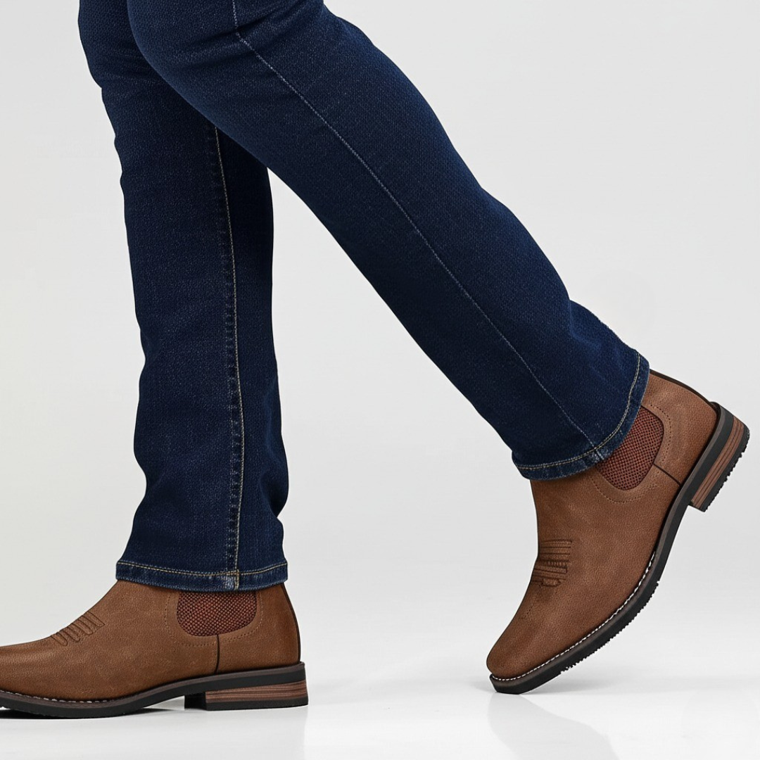 Model wearing tan leather Chelsea boots paired with dark denim jeans