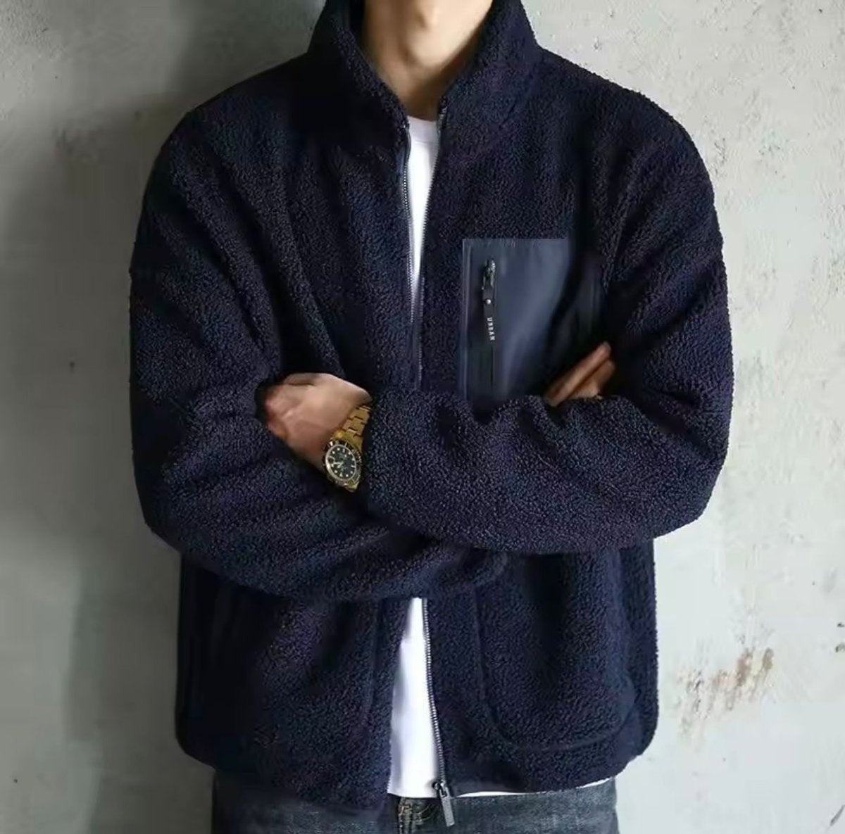 Navy sherpa fleece bomber jacket with zip chest pocket, worn crossed-arm