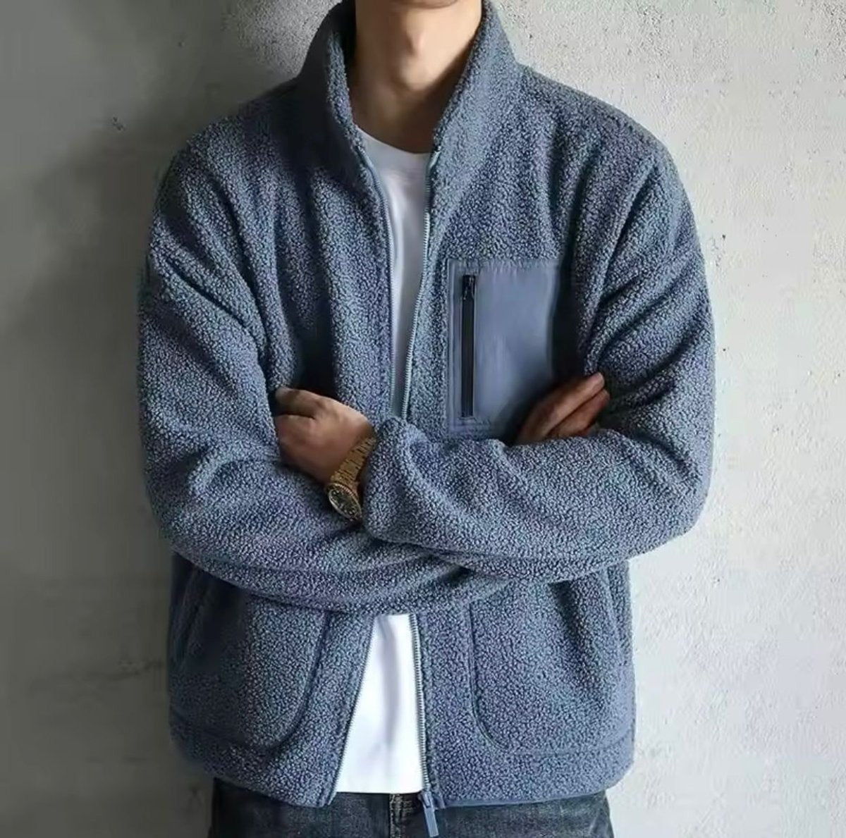 Steel blue sherpa fleece jacket worn with folded arms, showing zip pocket