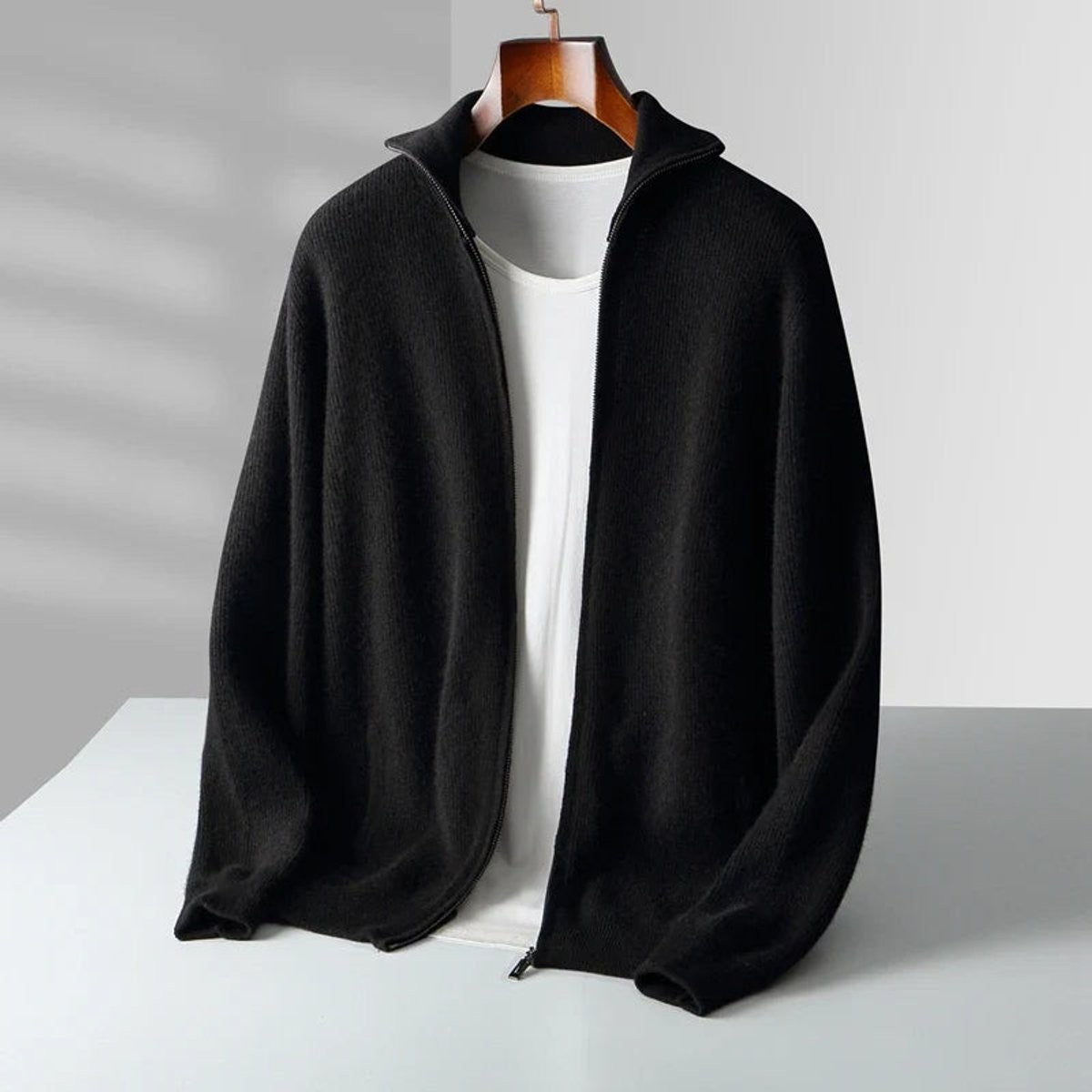 Black cashmere full-zip cardigan with ribbed knit texture, hanging display