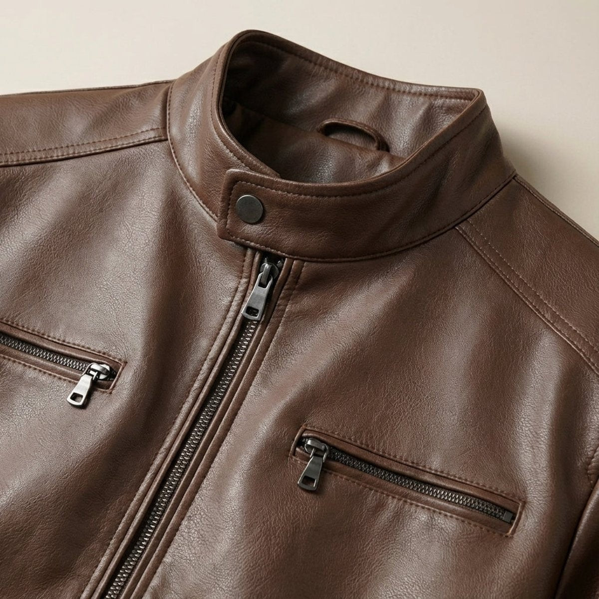 Close-up of brown leather jacket collar, snap button and zip detailing