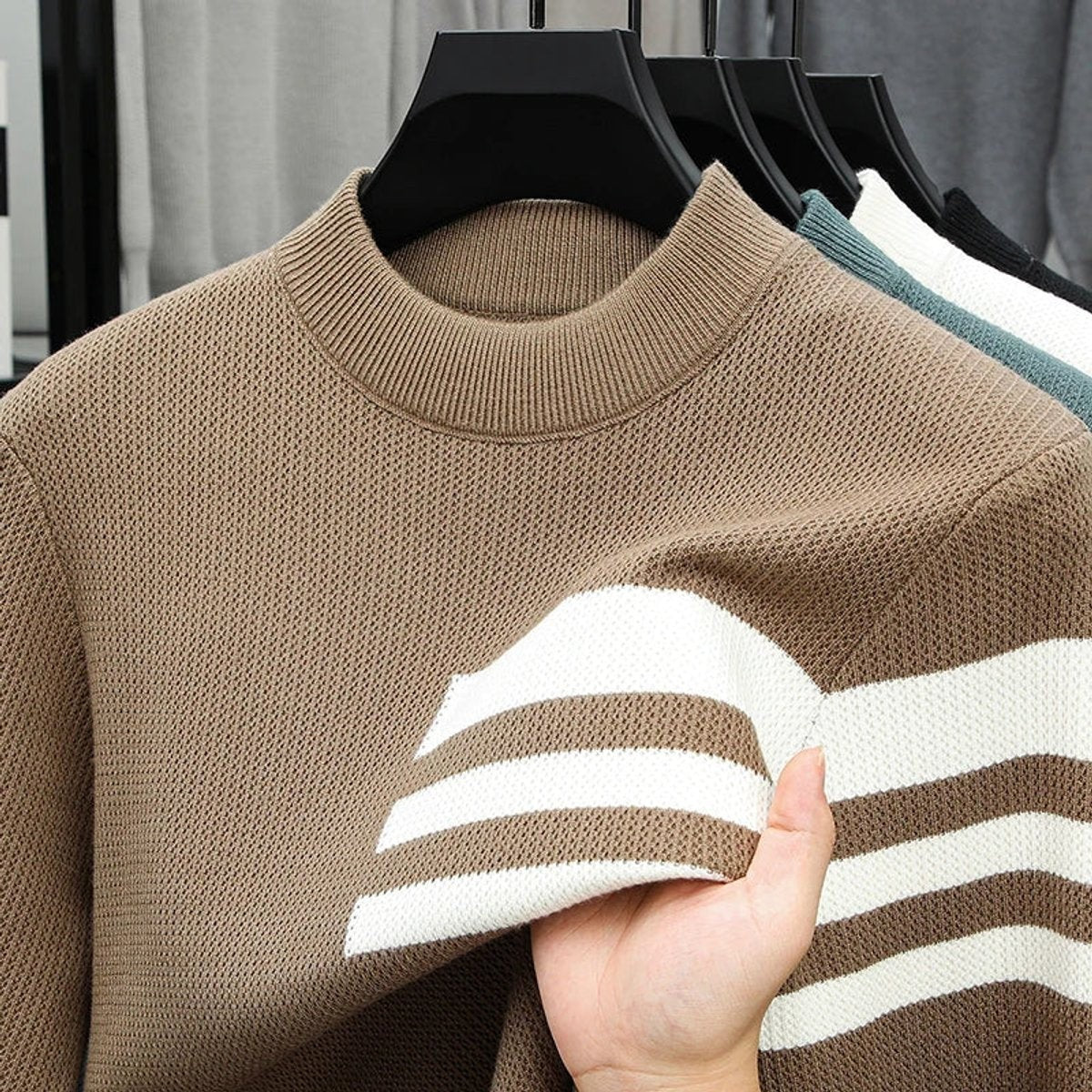 Taupe striped crewneck jumper with hand showing knitted fabric texture