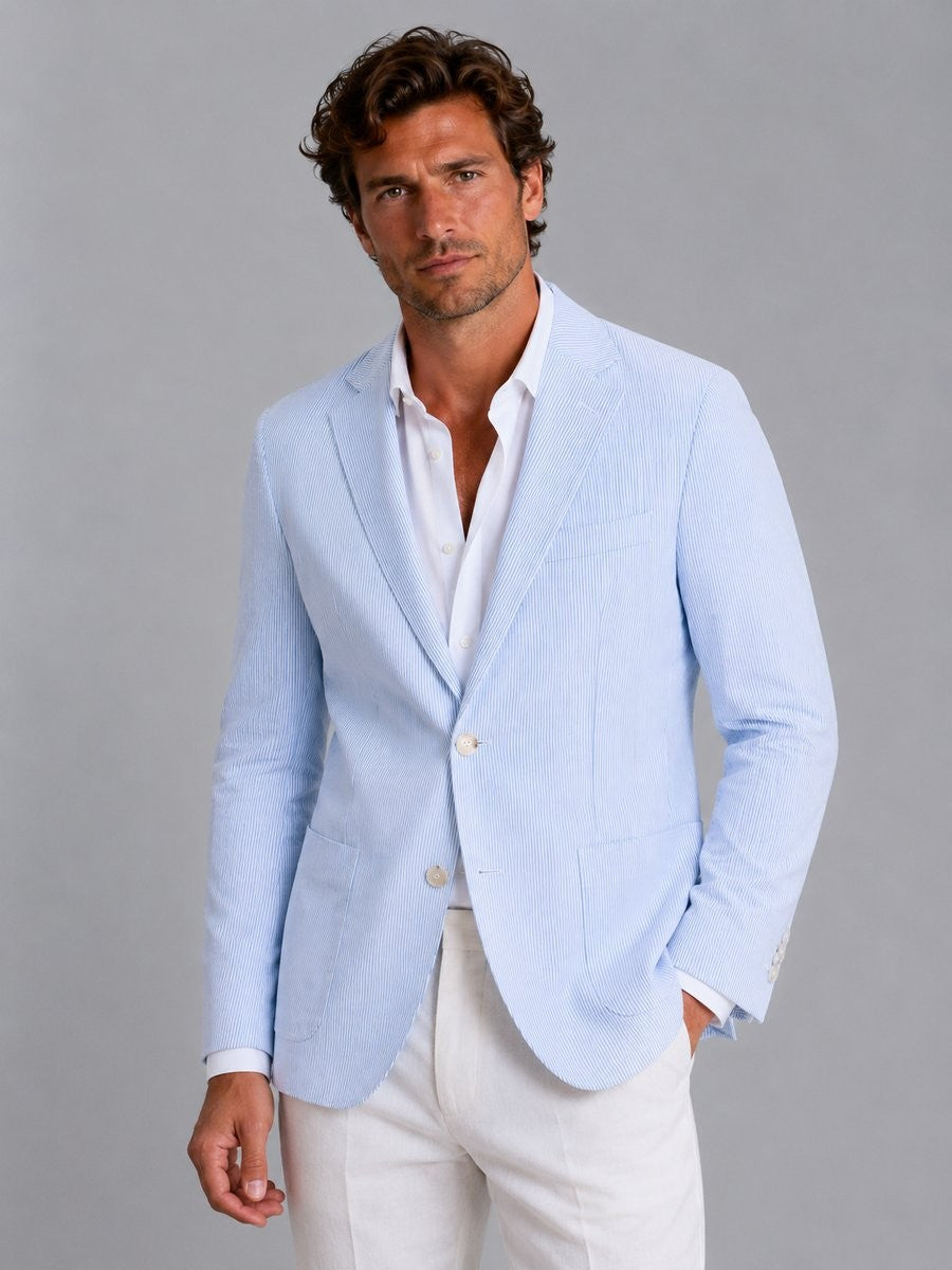 Man wearing light blue striped seersucker blazer with white linen trousers