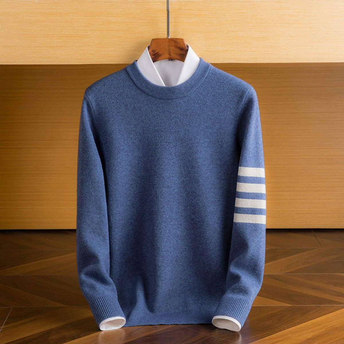 Blue lambswool crewneck jumper with striped sleeve detail on wooden hanger