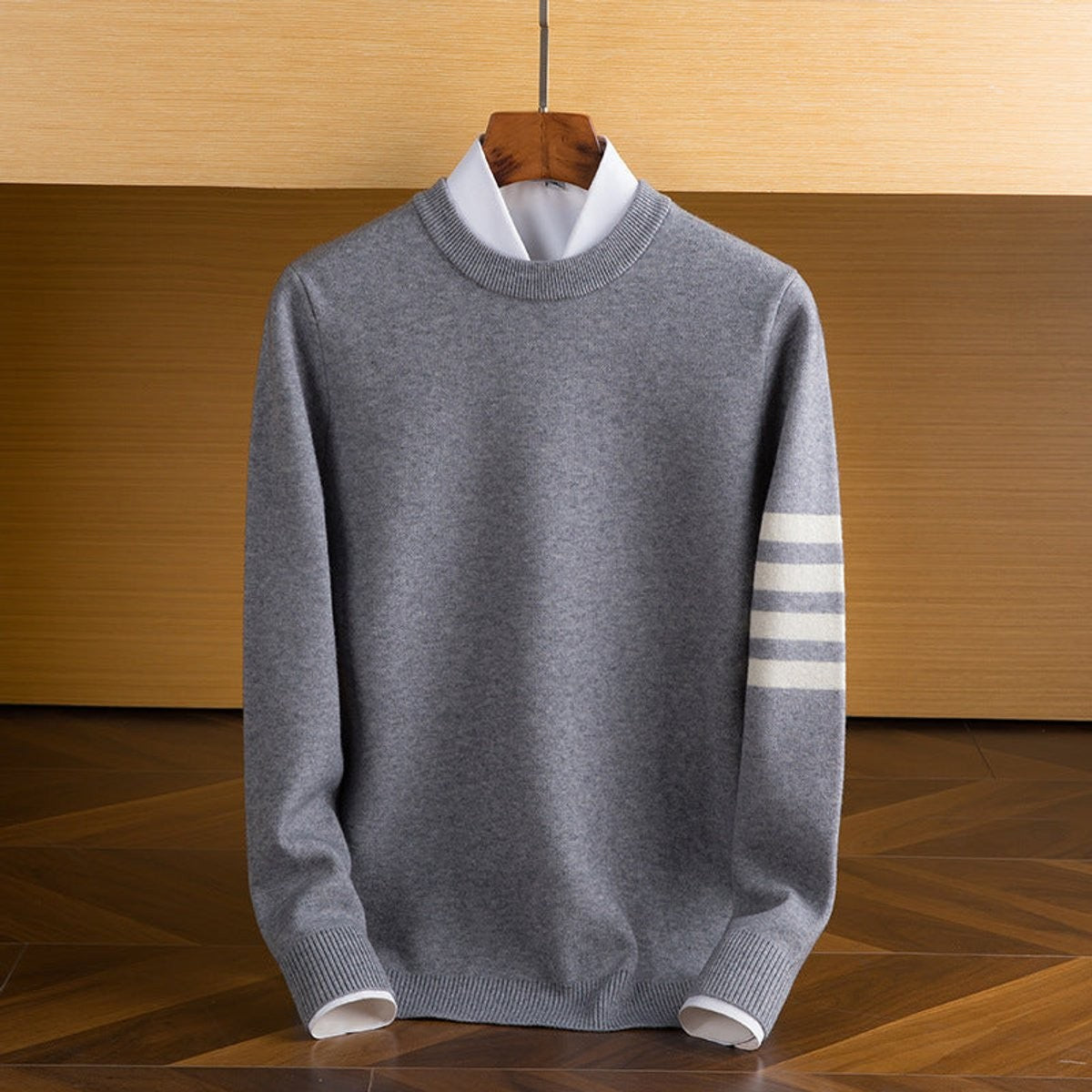 Grey knitted crewneck jumper showing subtle striped sleeve design