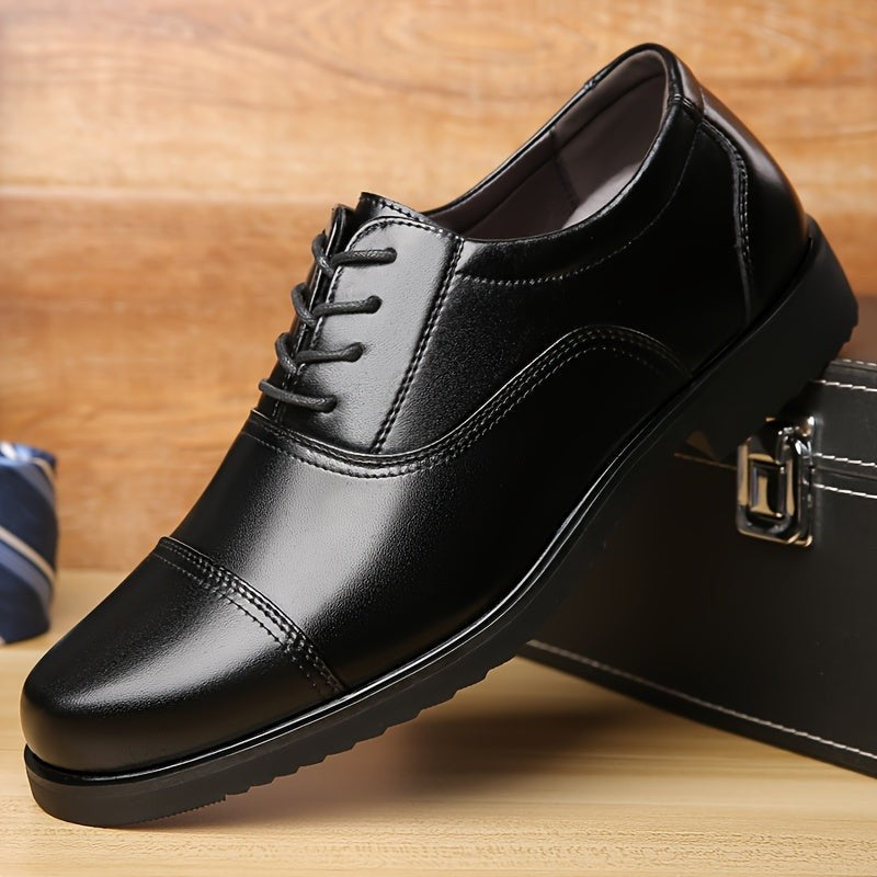 Men's black leather lace-up shoe with cap-toe detail beside briefcase