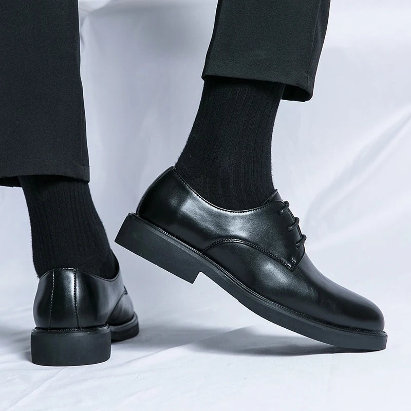Pair of black leather Oxford shoes displayed with wooden shoe trees