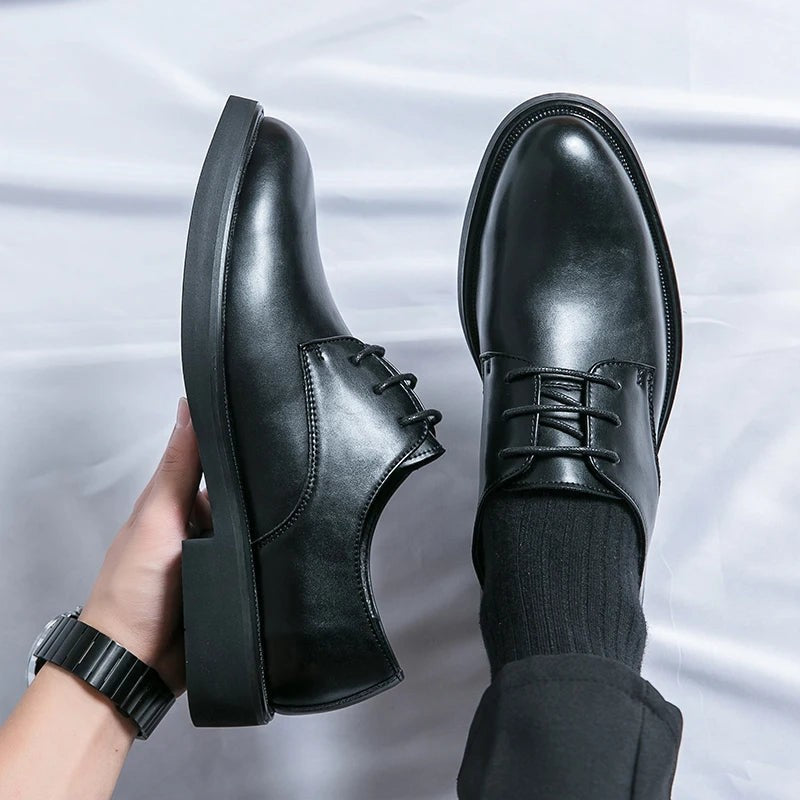 Close-up of brown leather Oxford shoe held beside foot wearing matching pair