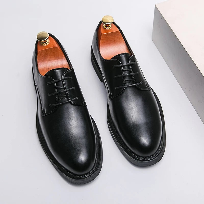 Close-up of black leather Oxford shoe held beside foot wearing matching pair