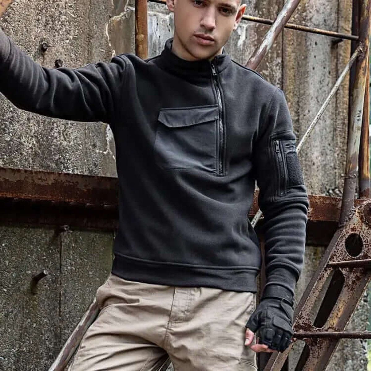 Man wearing black tactical fleece jacket against rusted metal backdrop