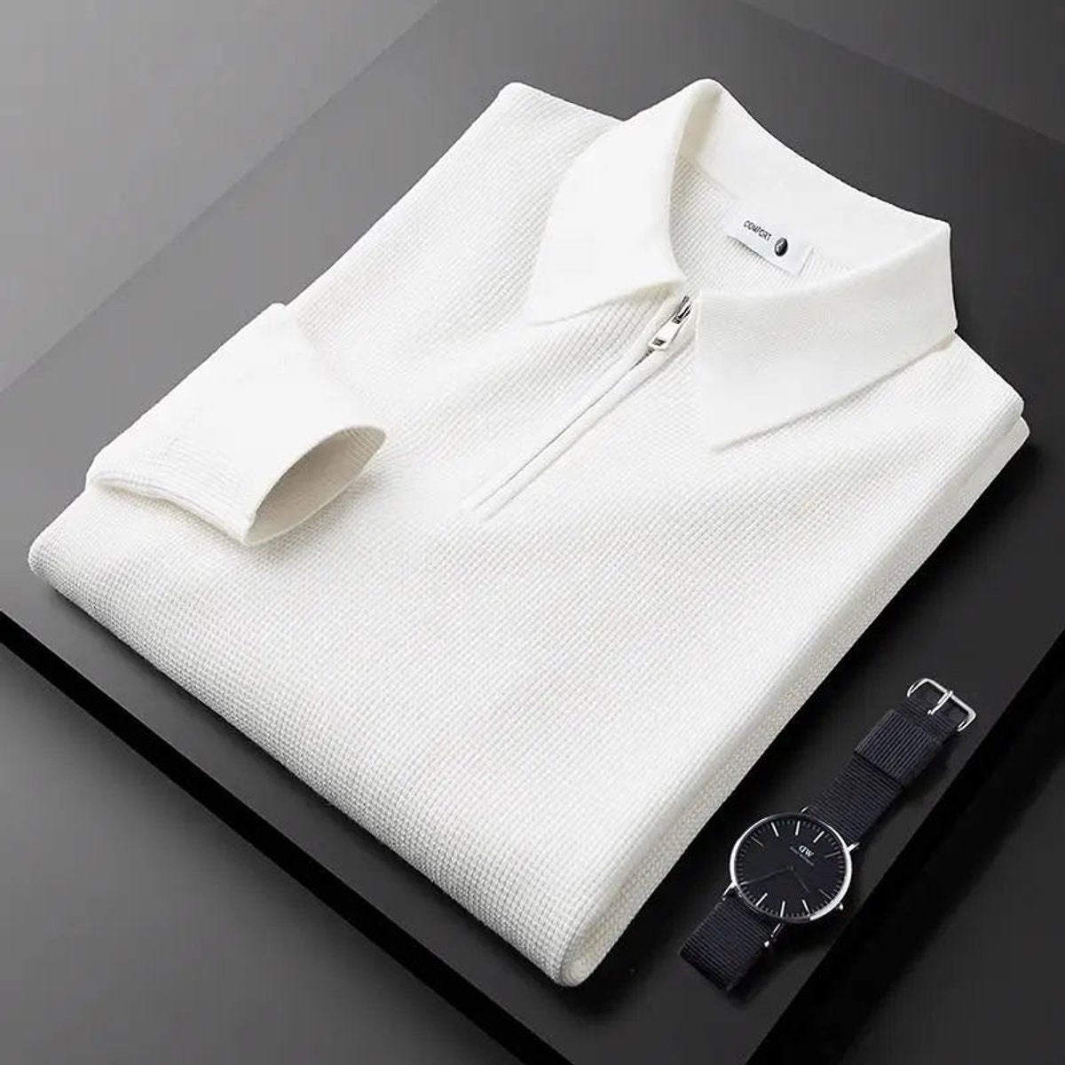 White quarter-zip knitted polo jumper folded beside a black wristwatch