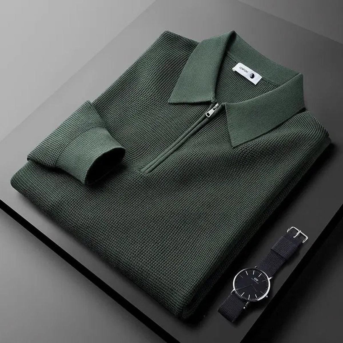 Dark green quarter-zip knitted polo jumper folded with a wristwatch